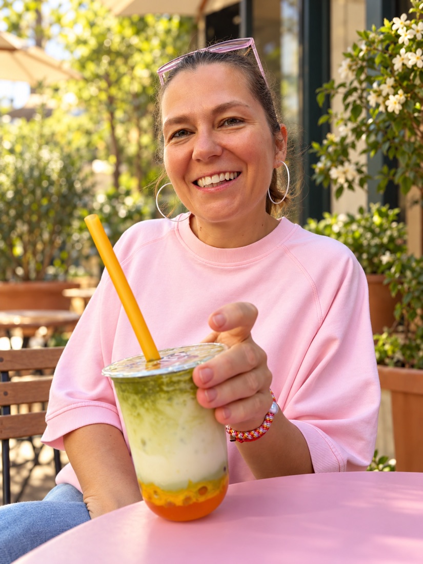 Gabriela genießt lächelnd ein Getränk im Café